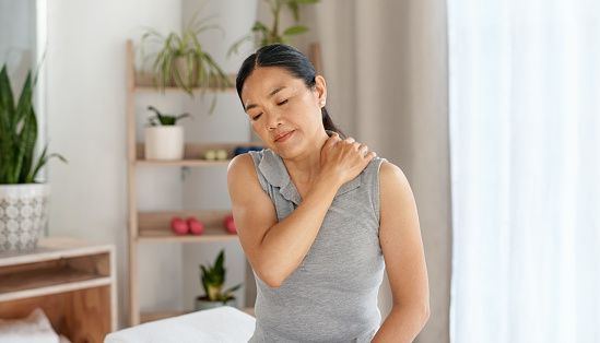 Mature, woman and shoulder pain in a living room with injury, muscle or suffering with inflammation. Spine, neck or arm ache for lady in her home with arthritis, osteoporosis or tension from stress