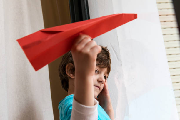 istock Child looking through a window with a paper plane. 1468456814