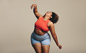Fit plus size woman dancing and having fun, expressing herself in sport clothing