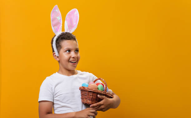 istock A Black boy with bunny ears on his head, a basket full of colored Easter eggs 1468457334