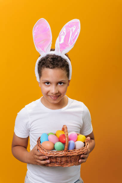 istock A Black boy with bunny ears on his head. A basket full of colored Easter eggs 1468457337