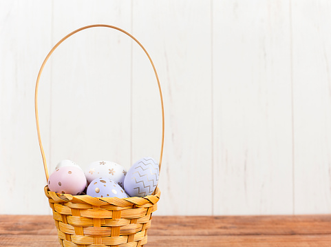 basket with colorful Easter eggs on a wooden table close up