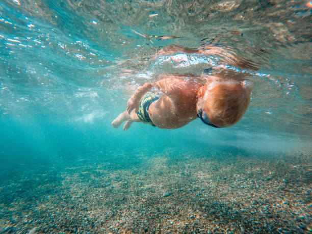 istock Young Caucasian Boy Floating In Clear Turquoise Colored Water 1468462544