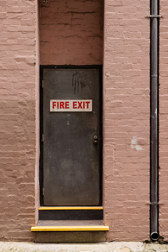 Old fire exit door in a painted brick wall.