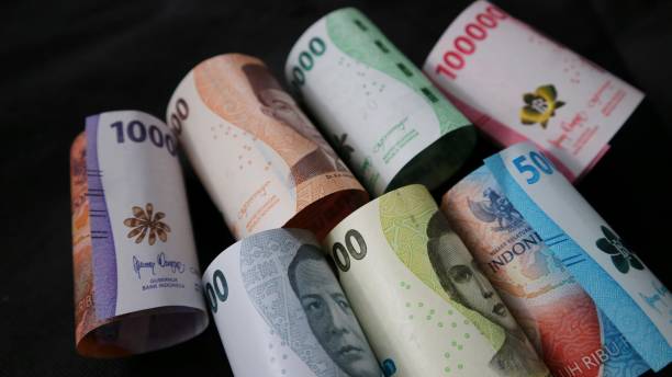 istock Rolled Indonesian Rupiah or IDR banknotes on the black background. Various denomination. Selective focus. Showing a picture of indonesian state hero figure in the banknote. 1468464904