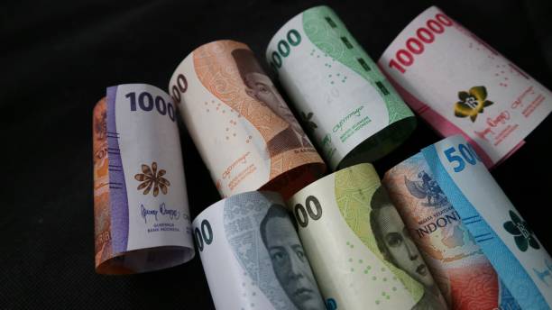 istock Rolled Indonesian Rupiah or IDR banknotes on the black background. Various denomination. Selective focus. Showing a picture of indonesian state hero figure in the banknote. 1468464938