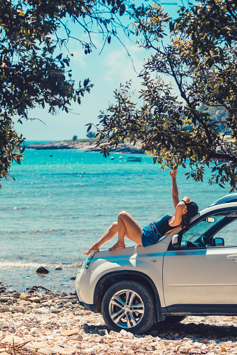woman sitting on car hood looking on the sea beach seaside summer vacation