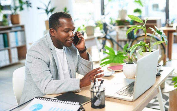 Phone call, business and happy black man at laptop in office, company or digital management. Manager, mobile talking and computer technology for networking, consulting and smartphone communication stock photo