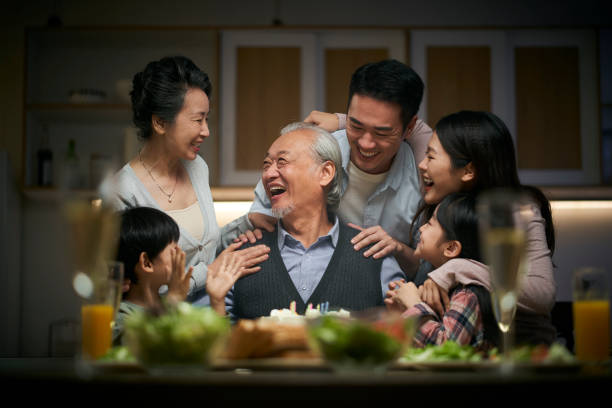 three generation asian family celebrating grandpa's birthday at home stock photo
