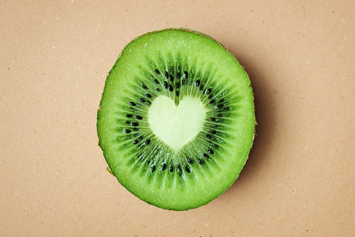 Heart shaped kiwi on recycled paper background - Kiwi is good for heart health