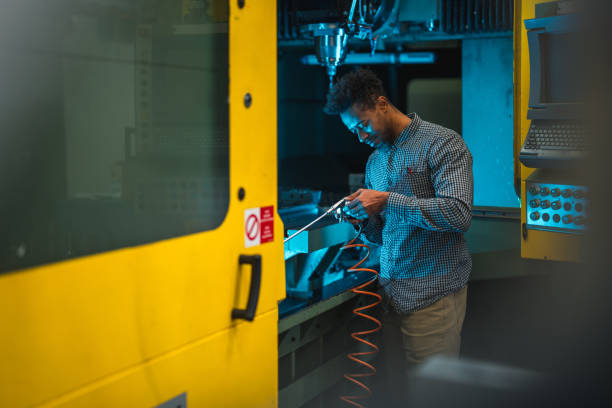 istock Focused Adult Mixed Male Electrical Engineer Holding A Milling Tool While Standing Next To The CNC Machine Control Panel 1468471970