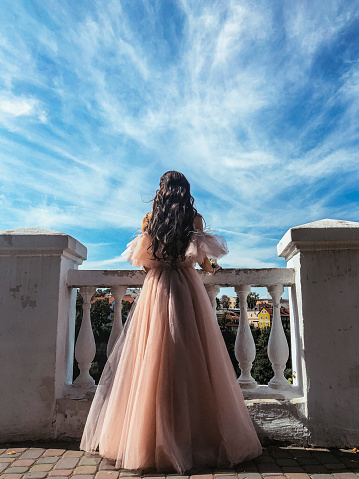 A woman in a lush dress is standing on a bridge