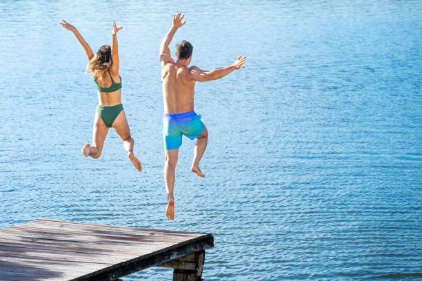 coppia saltando nel lago - arms raised green jumping hand raised foto e immagini stock