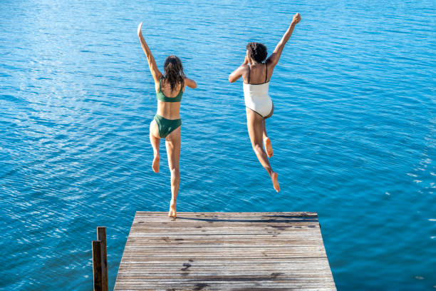 istock Female friends jumping in lake 1468473370