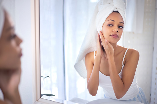 Skincare, beauty and face of black woman in mirror for cleaning, grooming and facial treatment at home. Bathroom, dermatology and girl check reflection for wellness, acne cosmetics and healthy skin