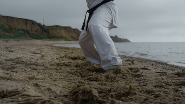 istock Man feets stepping on beach sand practicing karate overcast weather close up. 1468478720