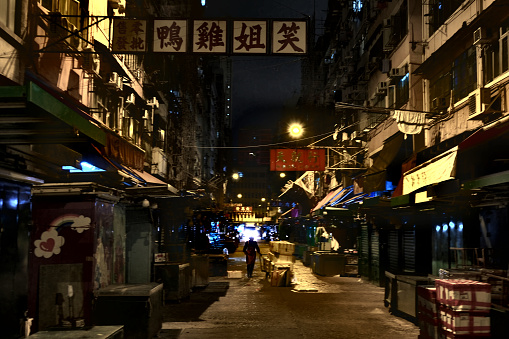 Man walking through a closed market in the Temple street area at night, Yau Ma Tei, Kowloon peninsula, 
Hong Kong.
