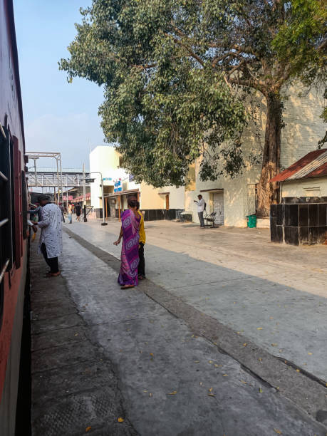 Stock photo of Indian railway platform, people boarding on train, old style white color painted Cabin at platform, Picture captured under bright sunlight. stock photo