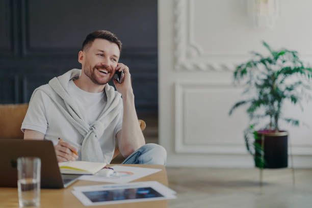 istock Happy freelancer talking on phone sitting at his work desk at home office 1468482323