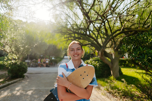 Photo of a smiling skater girl, who has found alternative way to commute to school - her  skateboard
