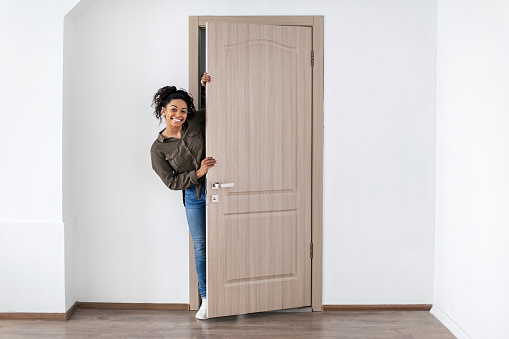 Real Estate Offer. Cheerful Black Woman Opening Door Smiling To Camera Posing In New Home. Apartment Rent And Purchase Service Concept. Full Length Shot