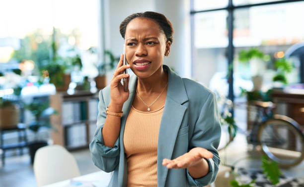 telefonata, litigio e donna conflittuale in ufficio che parla infastidita o arrabbiata al cellulare. dipendente africano sconvolto, lunatico e professionale che combatte con il fidanzato su uno smartphone sul posto di lavoro - telephone worried one person discussion foto e immagini stock