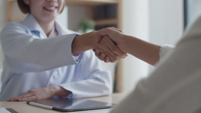 Close-up hand shaking medical student interviewing for hospital position with hospital staff.