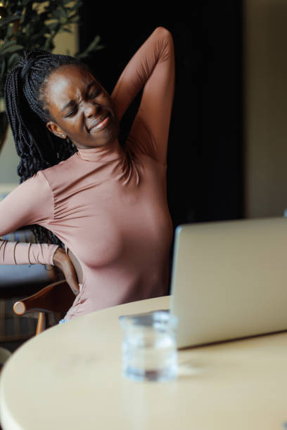 istock Afro american woman in nice turtleneck stretching back with closed eyes sitting on table and working on laptop in coffee house. Black girl working remotely, freelancer. Sore back, stoop, tiredness 1468487833