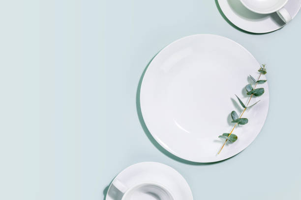 istock Empty dishes and cups with eucalyptus twig on blue background with copy space 1468488822