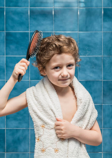 istock A boy with a towel on his shoulders brushing his hair. 1468489813