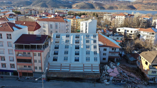 devido à liquefação do solo no terremoto na turquia, o edifício quebrou a fundação e caiu sobre o prédio atrás dele. - antakya - fotografias e filmes do acervo