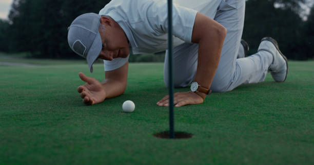 istock Professional golf player inspect golfing ball hole on green grass course field. 1468490922