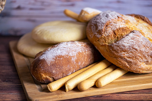 A board of some types of italian bread: breadsticks, loaf, arabic bread, focaccia