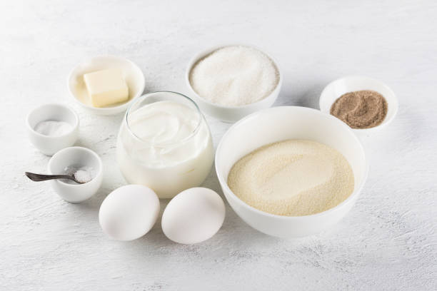 istock Ingredients for making a delicious semolina pie: semolina, eggs, sour cream or yogurt, sugar, vanilla sugar, butter, salt, soda on a light gray background 1468495400