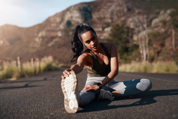 fitness, ritratto e stretching con una donna sportiva all'aperto su una strada in montagna per cardio o resistenza. esercizio, allenamento e riscaldamento con una runner che si prepara per una corsa nella natura - endurance sport foto e immagini stock