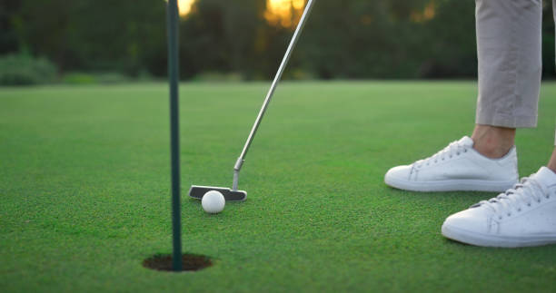 istock Golf club hitting ball in hole green course. Golfing player swing teeing putter. 1468495990