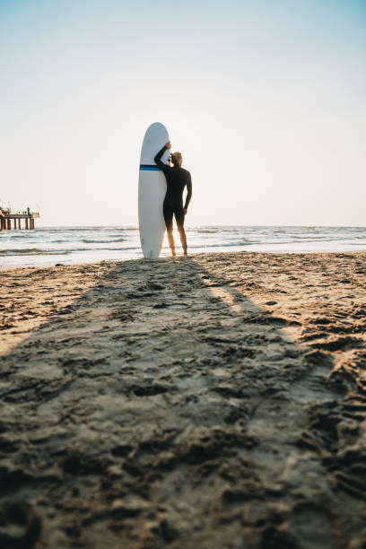 istock A man is standing on the beach with his surfboard, admiring the sunset 1468497167
