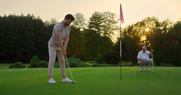 спортивные мужчины играют в гольф на поле. команда по гольфу проводит время на роскошном курорте. - putting together стоковые фото и изображения
