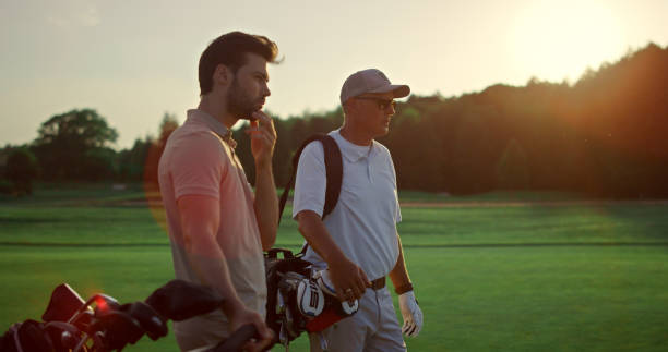 istock Rich men playing golf on sunset summer course. Two players enjoy sport on field. 1468497597