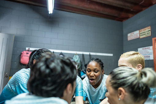 Female soccer team huddling in the locker room