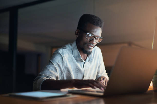 Worker, serious
 or reading laptop in night office of financial schedule, insurance budget strategy or investment target. Black man, businessman or ideas on late technology or finance data analytics stock photo
