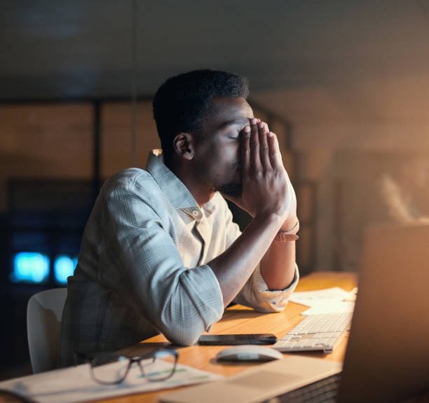 Depression, night or black man with headache in office for computer 404 glitch, coding anxiety or mental health. Sad, tired or developer on tech for programming stress, work burnout or software fail stock photo