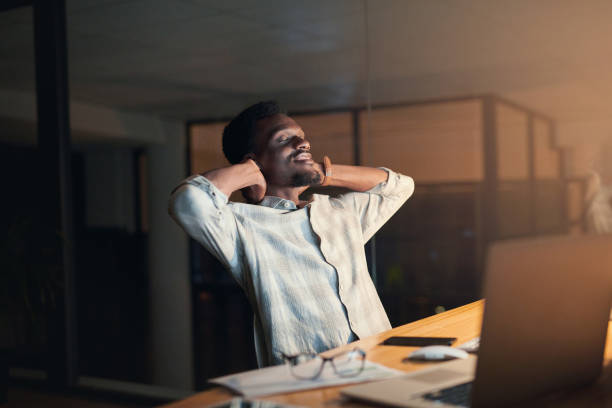 istock Relax, night and black man in the office on a break taking a nap after working on a project with a deadline. Tired, rest and exhausted African male employee sleeping by his desk in the workplace. 1468506400