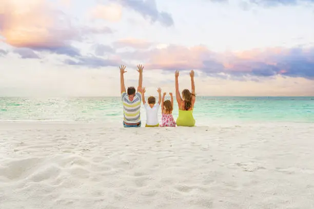 Photo of family by the sea enjoying the sunset on the beach.