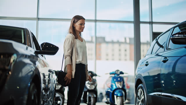 SLO MO Woman looks at a new car she likes most in a car showroom