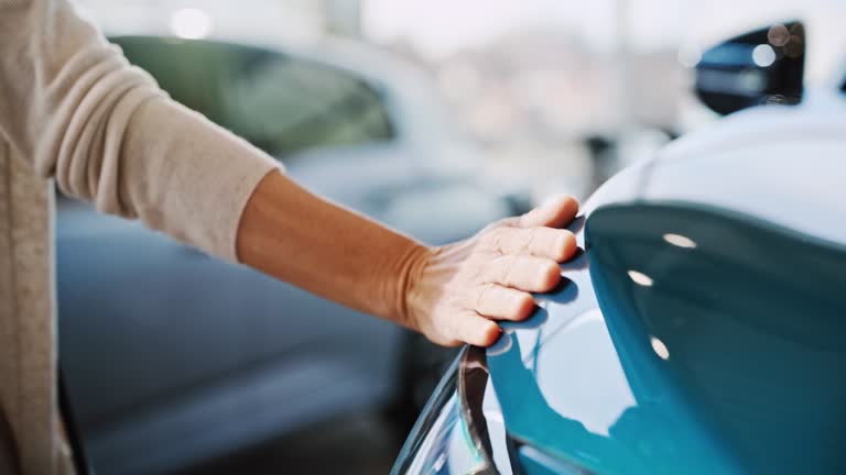 SLO MO Woman caress a car hood of a new car she likes most in a car showroom