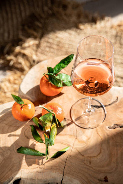 rosé wine glass on mediterranean chair with clementine citrus fruit in sunshine stock photo