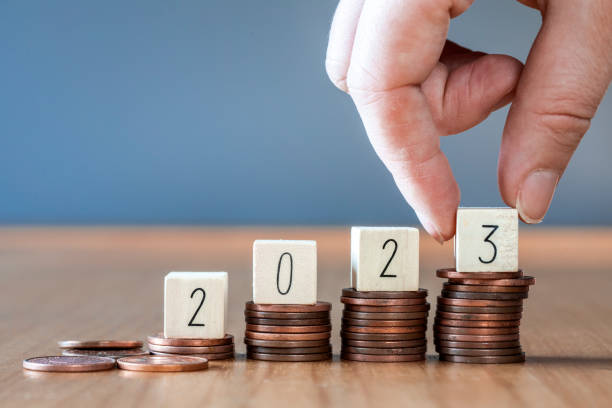 istock Hand place wooden cube 2023 on top stack of coins with sky blue background and copy space. saving money and financial plan concept for investment in new year 2023. 1468510060