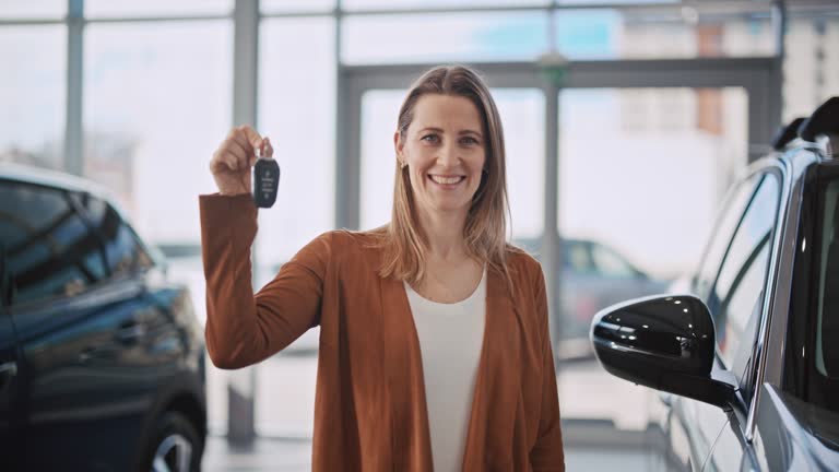 SLO MO Excited woman shows car keys of a new car she just bought it