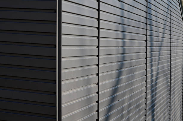 istock gray building is lined with square panels. metal sheet wall cladding with scalloped design. corrugated sheet, dark gray, riveted. horizontal stripes, shadows, corner, fence, aluminium, sheet 1468511362